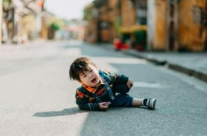 Crying Asian boy lying on road