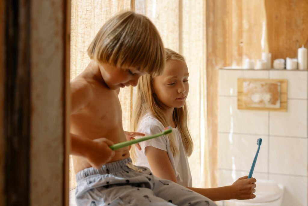 Two children brushing teeth together in a warm, sunlit bathroom promoting dental care.