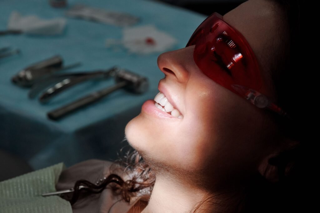 pexels-photo-4269691-4269691 Close-up of a woman smiling with protective glasses at a dental clinic, highlighting her teeth.