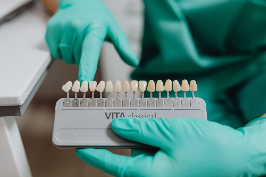 pexels-photo-6627292-6627292 Close-up of dentist using a tooth shade guide for accurate dental matching in clinic.